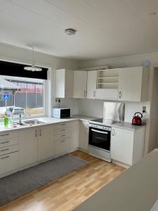 uma cozinha com armários brancos, um lavatório e um fogão em Apartment in the center of Tórshavn, free parking. em Tórshavn
