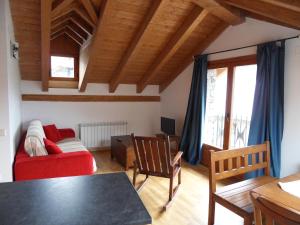 a living room with a red couch and a table at Pensió i Apartaments la Bordeta in Taüll