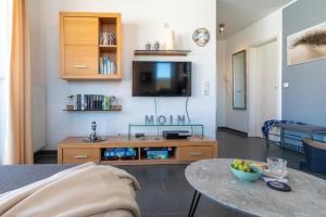 ein Wohnzimmer mit einem Tisch und einem TV in der Unterkunft Möwennest 8 in Großenbrode