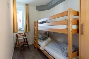 グローセンブローデにあるStrandpark-Grossenbrode-Haus-Moewennest-Wohnung-8-Typ-2の二段ベッド2台と椅子が備わる二段ベッドルーム1室です。