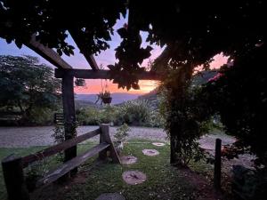 a bench sitting in the grass with a sunset in the background at Chácara paraíso dá paz in Nova Petrópolis