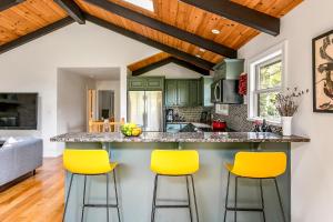 a kitchen with green cabinets and yellow bar stools at Woodpecker House - Mountain retreat with hot tub - 10 min to skiing in Hunter & Windham in Jewett