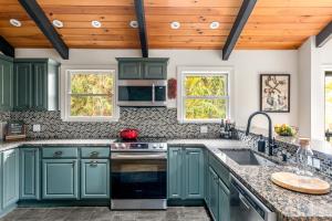 a kitchen with green cabinets and a wooden ceiling at Woodpecker House - Mountain retreat with hot tub - 10 min to skiing in Hunter & Windham in Jewett