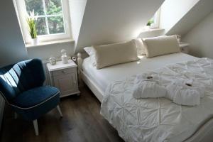 a bedroom with a white bed and a blue chair at +Idyllisches Apartement nahe der Ostsee+ in Biendorf