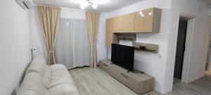 a living room with a white couch and a flat screen tv at Apartament Ghencea Residence 158 Floor 7 in Bucharest