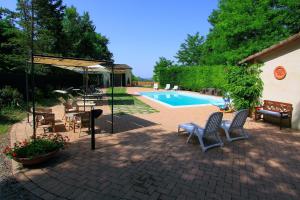 a patio with a pool and chairs and a table and an umbrella at Agriturismo Il Paradiso in Asciano