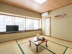 a living room with a table and a flat screen tv at SUIHOUEN in Numazu