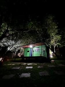 un edificio con una puerta verde por la noche en Pousada Cipó Container Chalés Privativos com lareira - Centro da cidade, en Serra do Cipo