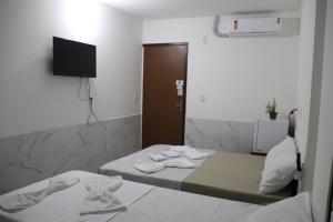 een kleine kamer met 2 bedden en een televisie bij Suítes Mar de Maragogi in Maragogi