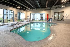 ein großer Pool in einem Gebäude mit Tischen und Stühlen in der Unterkunft Comfort Inn & Suites Buffalo Airport in Buffalo