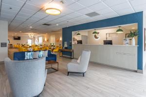 een wachtruimte van een ziekenhuis met stoelen en tafels bij Comfort Inn & Suites Buffalo Airport in Buffalo