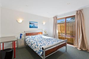 um quarto com uma cama, uma secretária e uma janela em The Blue Bay em Inverloch