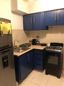 - une cuisine avec des armoires bleues et un réfrigérateur noir dans l'établissement Precioso apartamento, residencial ideal familia, à Saint-Domingue