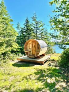 a wooden cabin sitting on a platform in the grass at The Cedar at Mira Riverfront Getaway in Marion Bridge