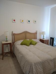 Un dormitorio con una cama con almohadas verdes. en Departamento con patio en Godoy Cruz