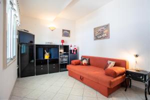 sala de estar con sofá naranja y TV en Apartments by the sea Zivogosce - Porat, Makarska - 6899, en Igrane