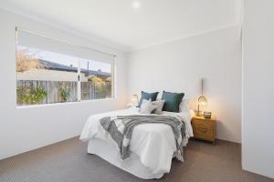 a white bedroom with a bed and a window at Halls Head Haven in Mandurah