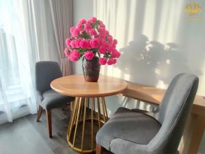 eine Vase rosa Rosen auf einem Tisch mit zwei Stühlen in der Unterkunft Hồng Gia Tuệ Lake View in Hanoi