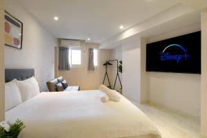 a bedroom with a large white bed with a tv on the wall at Members Hotel at Taipei 101 in Taipei