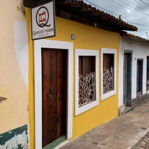ein gelbes Gebäude mit zwei Türen und einem Schild darauf in der Unterkunft Quinca’s Hostel in Lençóis