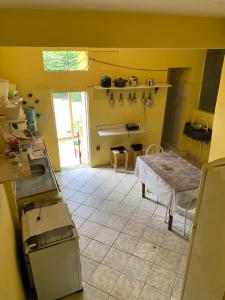una cocina con paredes amarillas y una mesa. en Quinca’s Hostel en Lençóis