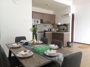 a dining room table with chairs and a kitchen in the background at Parc Regency Green Homestay By Easyhomestay in Johor Bahru