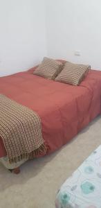 een bed met een rood dekbed en kussens erop bij Alborada in San Fernando del Valle de Catamarca