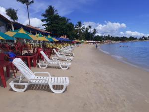 una spiaggia con sedie a sdraio, ombrelloni e l'oceano di Casa agradável em meio a natureza. a Santa Cruz Cabrália