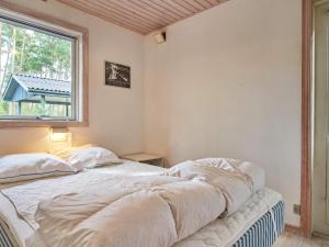 Cama blanca en habitación con ventana en Holiday home Aakirkeby XXXIX, en Vester Sømarken