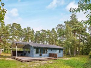 una pequeña casa azul con terraza en un campo en Holiday home Aakirkeby XXXIX, en Vester Sømarken