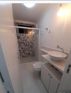 a bathroom with a toilet and a sink and a shower at Apartamento pé na areia in Guarujá