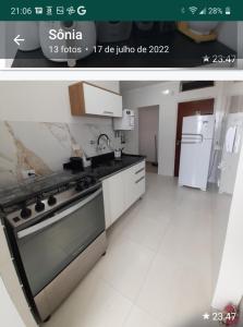 a kitchen with a stove and a refrigerator at Apartamento pé na areia in Guarujá