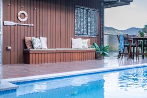 a patio with a bench next to a swimming pool at Holiday Haven Whitsundays in Cannon Valley