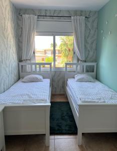 2 camas blancas en una habitación con ventana en Willa con piscina, en El Vendrell