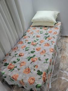 a bed with a flowery bedspread on it at Apartamento aconchegante com ar condicionado de 22 a 8h in Rio de Janeiro