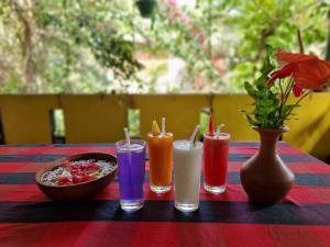 希卡杜瓦的住宿－Nimal`s Homestay，一张桌子,上面有四种不同的颜色饮料和一碗食物