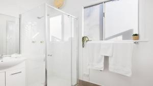 a white bathroom with a shower and a sink at Studio 21 in Nelson Bay
