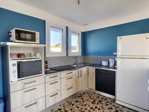 uma cozinha com electrodomésticos brancos e paredes azuis em Maison Jullouville, 3 pièces, 5 personnes - FR-1-361-334 em Jullouville-les-Pins