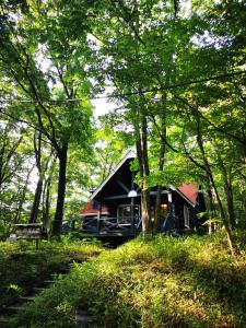 una cabaña negra con techo rojo en el bosque en 【那須高原の自然に囲まれたログハウス1棟貸し】ファミリー利用、大人数での利用、パーティも大歓迎！ en Nasu-yumoto