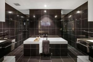 La salle de bains est pourvue d'un lavabo et de murs carrelés noirs. dans l'établissement Stunning Waterfront Penthouse 3 or 4 Bedrooms, à Brisbane