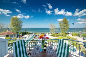 een balkon met een tafel en stoelen en uitzicht op het strand bij Hotel Wilhelmshöhe in Warnemünde