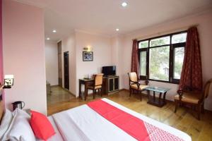 a bedroom with a bed and a desk and a window at Goroomgo Marc Shimla Near Mall Road - Luxury Room - Excellent Service - Ample Parking - Best Hotel in Shimla in Shimla