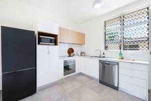a kitchen with white cabinets and a black refrigerator at 'Botanica Hermosa' Enjoy the Best of Nightcliff in Nightcliff