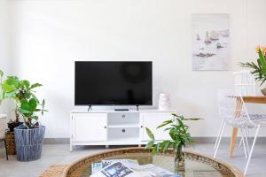 a living room with a tv on a white cabinet at 'Botanica Hermosa' Enjoy the Best of Nightcliff in Nightcliff