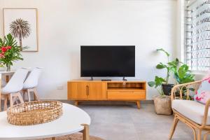 a living room with a flat screen tv on a wooden entertainment center at 'Botanica Fresca' Chic Nightcliff Convenience in Nightcliff