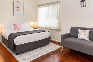 ein Schlafzimmer mit einem Bett und einem Sofa in der Unterkunft Pacific Motel 03 in Forster