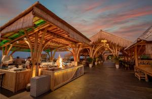 The Nest Hotel Nusa Dua في نوسا دوا: مطعم بجناح خشبي كبير مع طاولات