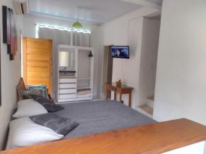 a bedroom with a large bed and a kitchen at Recanto dos Pássaros in Ilhabela