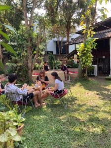 een groep mensen die rond een tafel in het gras zitten bij Easy house in Pai