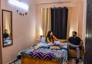 瑞詩凱詩的住宿－Skyard Rishikesh, Laxman Jhula，坐在酒店房间床上的男人和女人